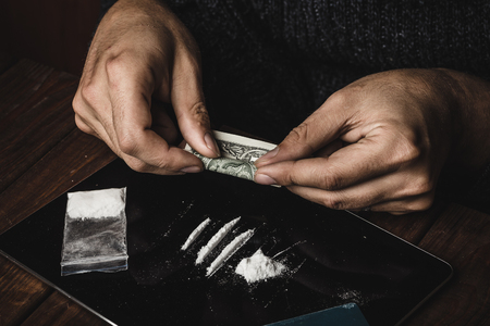 Man hands rolls dollar banknote for using cocaine powder lines, Drug addiction conceptの写真素材