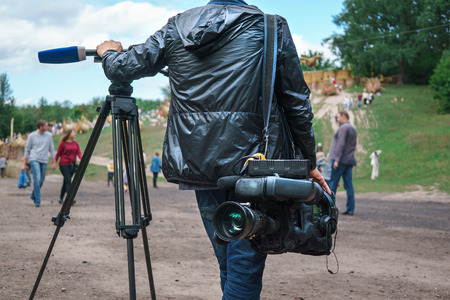 Professional video operator or videographer or cameraman standing with tripod and digital camera at...