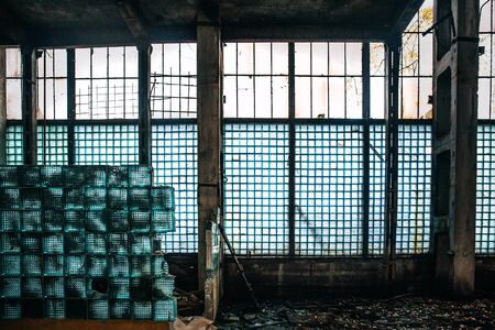Dark creepy abandoned industrial building inside with broken ruined wall from glass blocks, tonedの写真素材