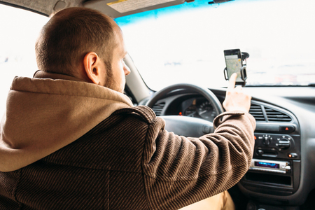 Man driver in car touching by hand smartphone screen with application navigation system, GPS using in transportation and travel concept, tonedの写真素材
