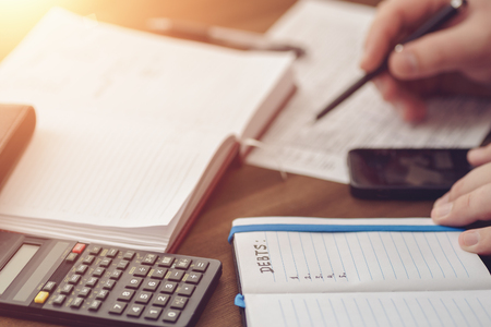 Budget planing concept. Calculating of bills, taxes, credits, payments and debts, paperwork with notebooks and calculator for expenses and finance. Selective focus with light effect, tonedの写真素材