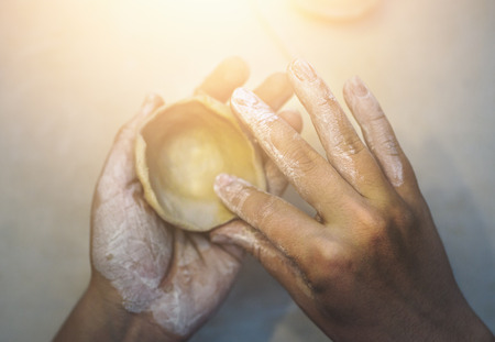 Female potter works with clay, craftsman hands close up, toned. Top view of molding shape to clay...