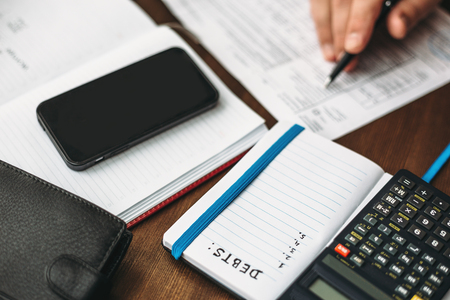 Budget planing concept. Calculating of bills, taxes, credits, payments and debts, paperwork with notebooks and calculator for expenses and finance. Selective focusの写真素材