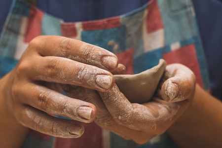 Female potter works with clay, craftsman hands close up, toned.の写真素材