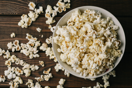 Popcorn in bowl on wooden background, top view, retro tonedの写真素材