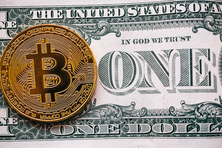Cryptocurrency golden bitcoin coin on one dollar banknote - symbol of virtual money and old paper money, tonedの写真素材