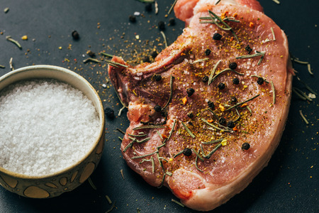 Raw meat, beef steaks with spices on dark background, top viewの写真素材