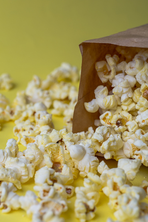 Popcorn in paper bag on yellow table, vertical imageの写真素材