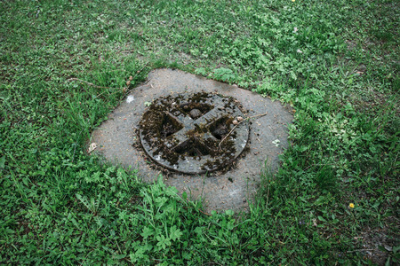 old vintage sewer hatch amid a clearing with green grassの写真素材
