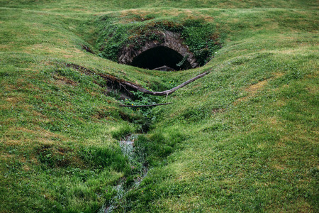Old wastewater or savage brick pipe in hill with green grassの写真素材