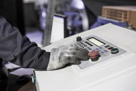 Worker hand on control panel with buttons of CNC plasma metal cutter, industrial metalworking factory, tonedの写真素材
