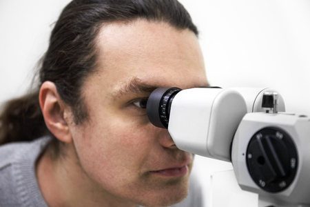Optometry concept. Doctor tests eyesight diagnostic of patient by modern ophthalmology equipment in clinicの写真素材