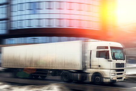 White truck transportation on city road at urban background, motion blur effect with sunlight, tonedの写真素材