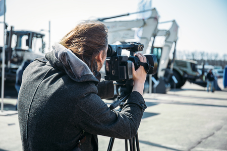 Cameraman or reporter works on street, view from back