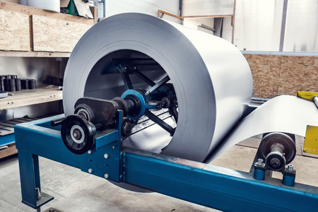 Metal sheet roll in industrial forming machine at factory workshop, stainless steel and metalwork manufacturing, tonedの写真素材