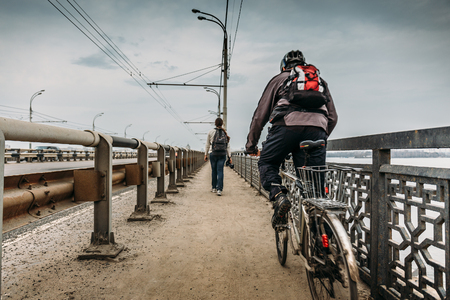 Urban scene at city bridge : biker on bicycle and traveler with backpack, view from back, travel concept, vintage tonedの写真素材