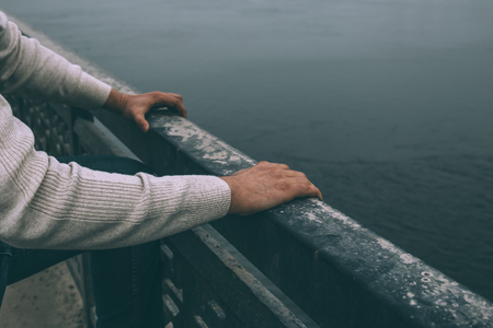 Depressed man is going to jump from bridge, close up view on hands. Suicide concept.の写真素材