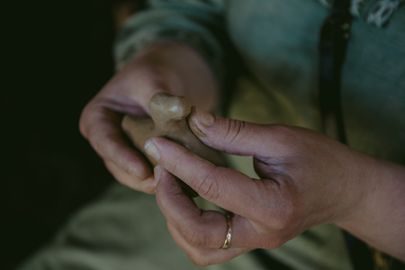 Potter works with clay, craftsman hands close up, kneads and moistens clay, tonedの写真素材