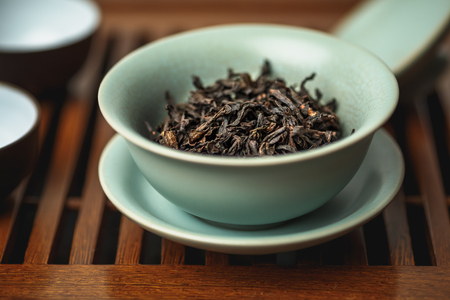 Chinese tea ceremony, da hong pao oolong tea in gaiwan or tea-cup on a wooden table