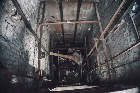 Broken Lift or elevator shaft or well in abandoned industrial ruined factory, tonedの写真素材