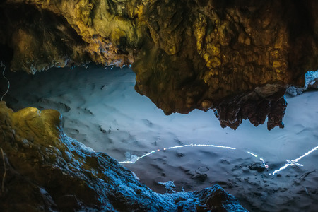 Beautiful illuminated limestone stalactites in Adygeya cave,  underground river with reflection of...