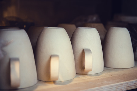 Clay pottery ceramic mugs products dry on shelf in workshop, tonedの写真素材