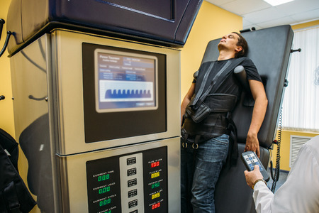 Male patient at non-surgical treatment physiotherapy of lumbar spine and spinal cord dilatation in medical center on special medical machine equipmentの写真素材