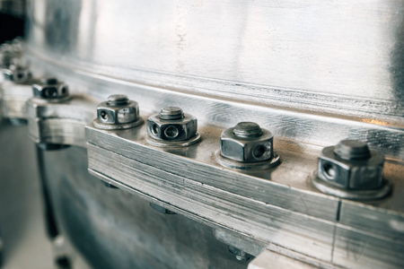 Joint of flanges by bolts and nuts, close up. Flanged vacuum equipment. Shiny metal surface as...
