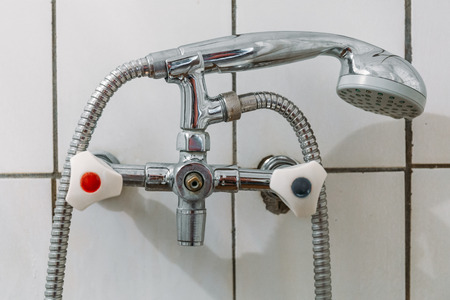 Old steel shower faucet at white vintage tile background, close upの写真素材