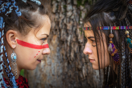 Two girls in image of Native American warriors looks at each other, standoff and battle of views...