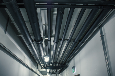 Industrial heating pipes under celling or another household communications pipelines in modern building, perspectiveの写真素材