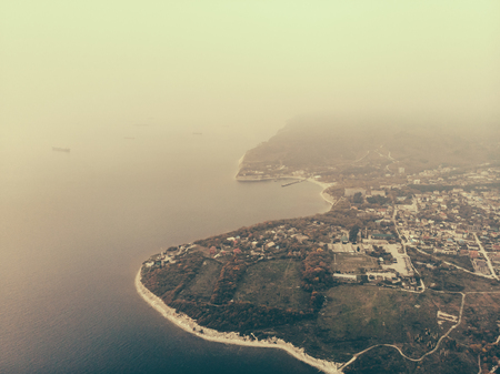Aerial view panorama of ocean or sea coast with city buildings in foggy weather, tonedの写真素材