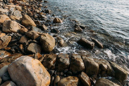 Stone beach at sea shore, close up. Ocean water waves at sunset, relaxation and tranquil nature background with copy spaceの写真素材
