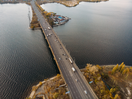 Aerial panoramic view of big river and transportation bridge over it with cars in autumn European city.の写真素材