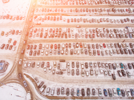 Aerial view of large automobile parking lot with many cars near mall or shopping center in winter with snow and sunlight effect, drone photo from aboveの写真素材
