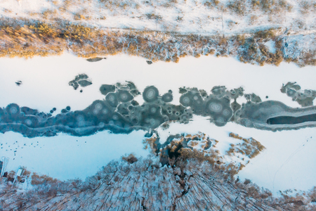 Frozen river, aerial or top view from drone of winter landscape with snow and lake or river in ice, abstract nature background.の写真素材