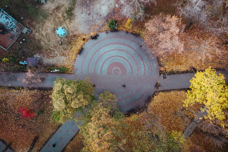 Aerial top view of autumn city park with concrete paths, round in center and walking people, drone shotの写真素材
