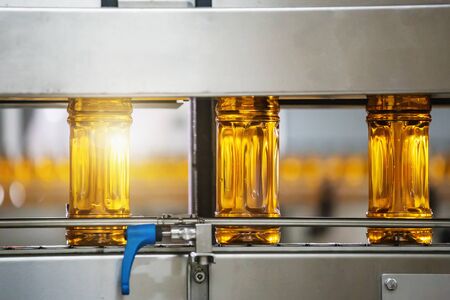 Bottles with fresh organic juice or sunflower oil on automatic conveyor belt in factory interior inside with modern industrial machine equipment.の写真素材
