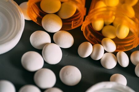 Treatment medication concept. Withite pills or drugs and orange pill bottles, selective focus.の写真素材