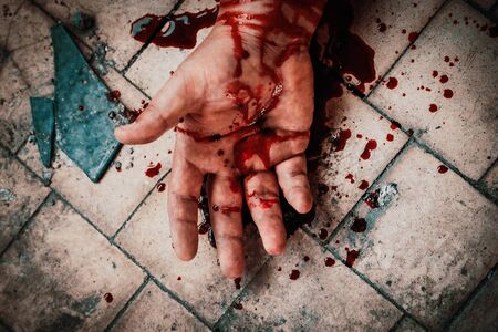 Crime scene with human hand in blood on floor of killed man by murder, dead body part close up.の写真素材