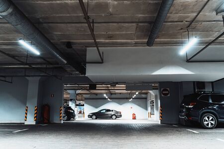 Illuminated underground car parking interior under modern mall with vehicles, tonedの写真素材