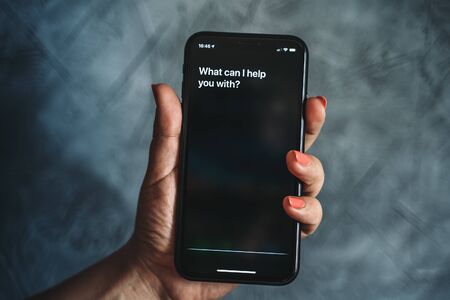 Moscow, Russia - Circa August 2019 : Siri - Apple voice assistant activated by voice in female hand and text on Iphone screen: What can I help you with? Voice mode of interaction with smartphoneのeditorial素材