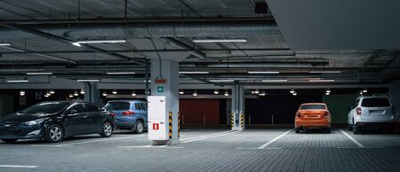 Panoramic image of Illuminated underground car parking interior under modern mall with vehicles, tonedの写真素材