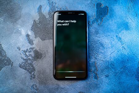 Moscow, Russia - Circa August 2019 : Iphone on concrete surface and activated by voice Apple digital assistant Siri and text on smartphone screen: What can I help you with?のeditorial素材