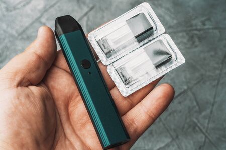Vape pod in male hand or pod mod with changeable cartridges close up - newest generation of vaping...