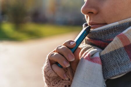 Young girl holds in hand new Vape Pod System, electronic cigarette, vaping concept.