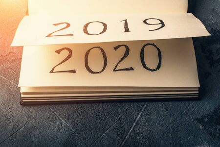 Notepad or calendar with pages and text 2020 and 2019 in sunlight. New year, new beginnings and...
