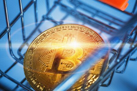 Shining gold Bitcoin coin in a shopping cart, blue toned.