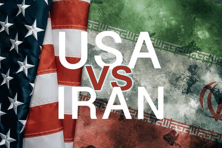 USA vs or versus IRAN - inscription over American flag and Iranian flag on grunge background. Problems and conflict with relationships between two countries concept.の写真素材