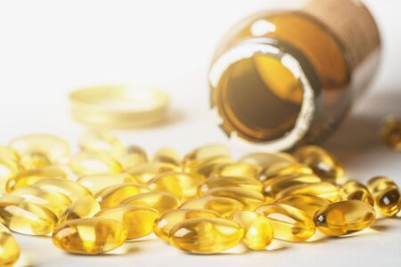 Omega 3 yellow capsules and pill bottle on white background. EPA and DHA are two types of Omega-3...